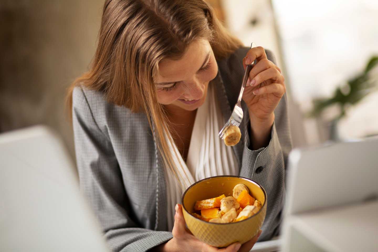 A woman at an office enjoying a bowl of fruit from her company's Office Pantry. Office Pantry Service​ from Avcoa Vending, Chicago, IL