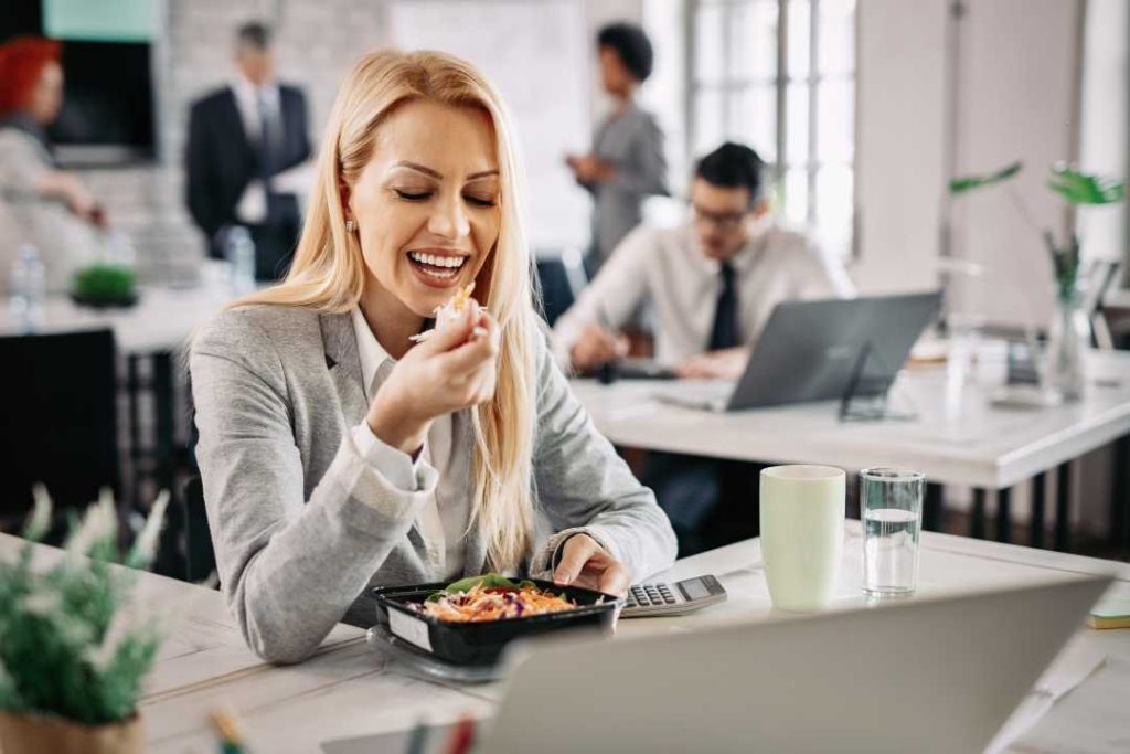 A woman in a busy office enjoying a delicious salad provided by the top-tier office vending services from Avcoa Vending in Chicago, IL.